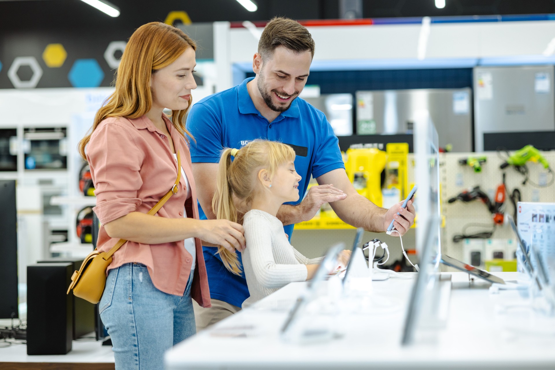 Mother and daughter exploring electronic devices in a modern retail store